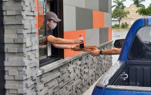 Blaze Pizza employee handing food through a drive-thru.